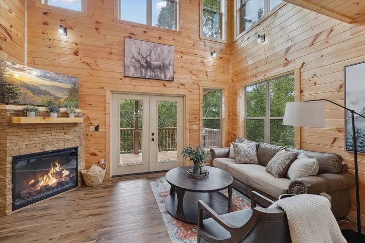 Living room with high wooden ceilings, a stone fireplace, and a sofa.