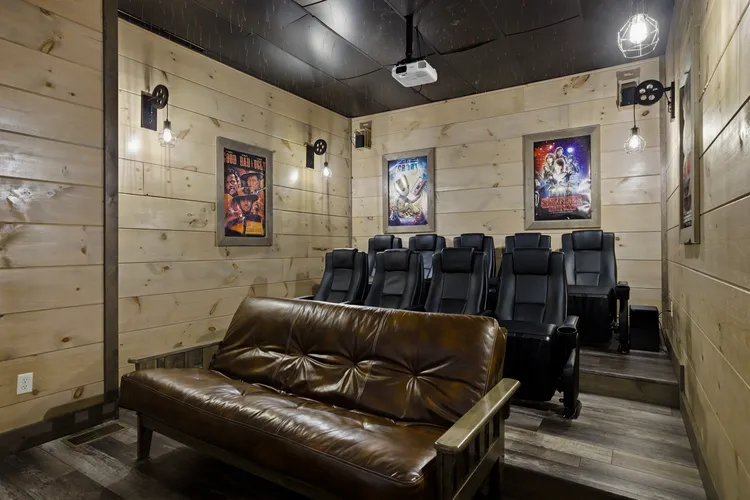 Home theater room with brown leather sofa and black recliner seats.