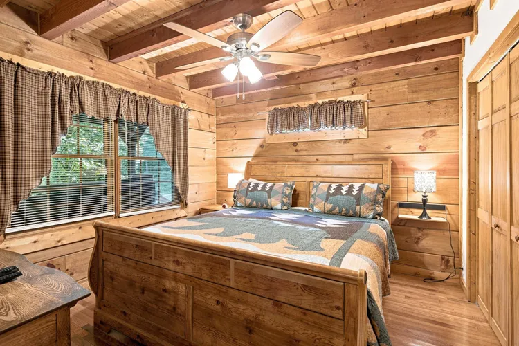 Bedroom with wood-paneled walls, wooden bed, and ceiling fan.