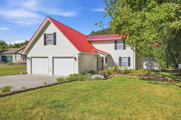 Front exterior view of house with red roof, attached garage, and lawn.